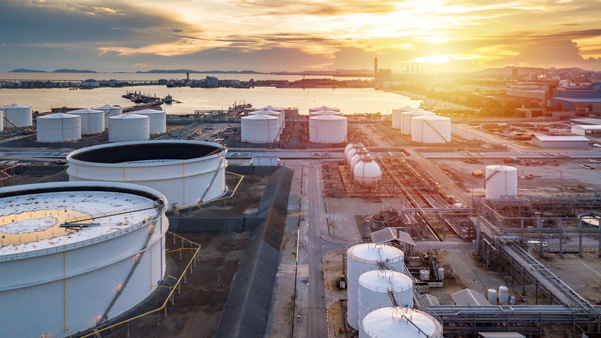 Bulk liquid storage terminal with tanks and transfer infrastructure at sunset