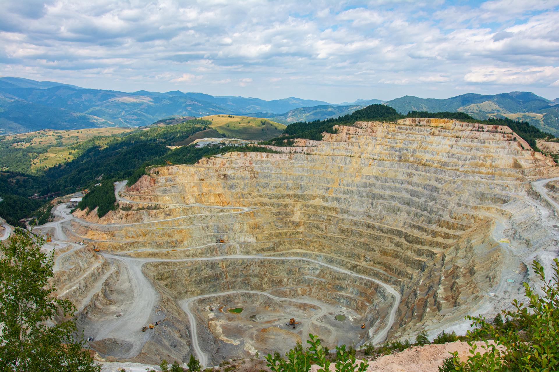 Large open-pit mine surrounded by forested mountains